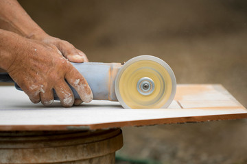 Fototapeta premium Image of worker using tool to cut white tile.