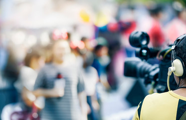 Fototapeta premium Video camera man working outdoors with young woman reporter.