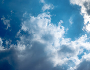 Fototapeta premium Blue sky with white clouds and gray cloud blue sky on a bright day with white clouds coming in floating come to cover sun causes a white beam causing beauty in the sky.