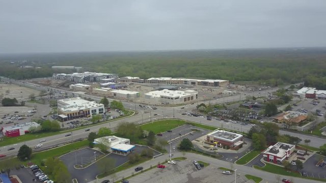 AERIAL: hyper lapse push towards a popular intersection with a shopping mall under construction in the background.