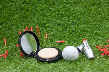 Naklejka premium Golf ball with powder and lipstick for lady golfer on green grass for golfer beauty concept