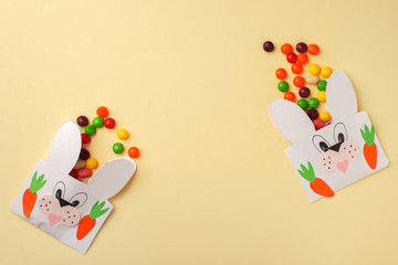 Easter colorful candy and Jellybean flowing from party paper handcraft bag on yellow white background. Easter bunny package. copy space, flat lay, Happy Easter concept