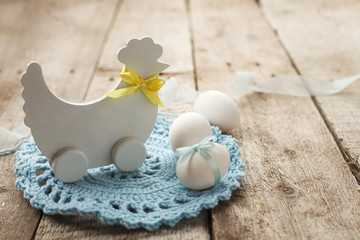 Rustic Easter background with wooden decorative chicken and chicken eggs on old vintage wooden board with blank space for text