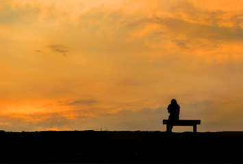 Obraz na płótnie Canvas silhouette of woman relax on chair happy time sunset