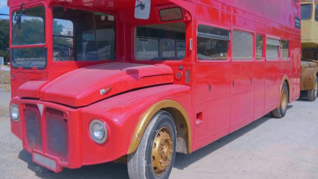 The legendary English red double decker bus as a symbol of the UK, parked paired with another yellow bus. Shot in motion