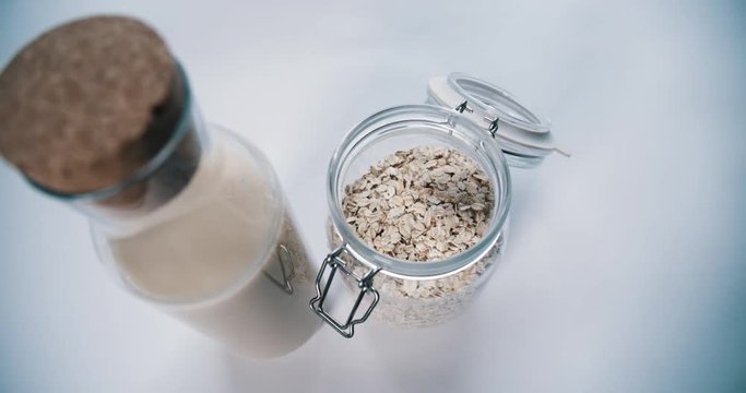 Fresh oat milk alongside rolled oats on breakfast table