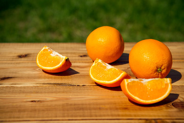 sliced and whole oranges on a wooden table.
