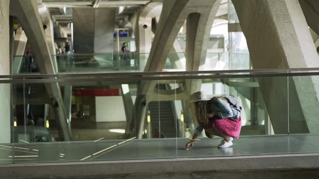 Side view of woman with backpack dropping passports while walking on modern train station or airport terminal in big capital city
