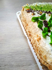 Beautiful fresh delicious cake stands on a clean table in a disposable plate. Oil cream and finely chopped nuts. Photo for a restaurant or cafe menu
