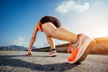 Naklejka premium An asian woman athletic is jogging on the concrete road, she is warming her body and tideten her tying her shoes tightly fitting before workout.