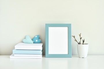 Light blue interior, blank photo frame mockup, books, white and blue decorations.