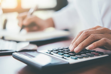 Woman with bills and calculator. Woman using calculator to calculate bills at the table in office....