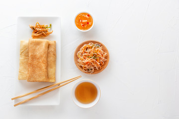 Traditional snacks of Chinese cuisine Dim Sum - tortillas - bings in a plate on a white background, spicy salads, vegetables, noodles. View from above.