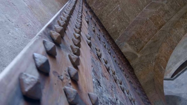 Large old wooden gates in the passage to the inside the ancient Spanish castle are trimmed with metal spikes. Shot in motion