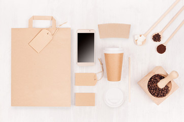 Coffee shop template for branding identity - brown paper cup with blank bag, phone, label, card, mortar with coffee beans on white wood board, top view.