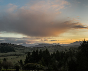 Sunset over Oregon's Willamette Valley with Oak trees on Bald Hill, and farmland, and Douglas Fir trees in the foreground.