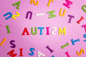 The word autism and multi-colored letters on a purple background. Autism Awareness Day.