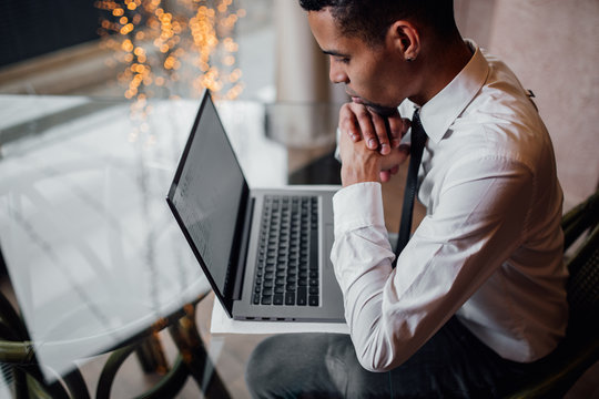 African American man looking at laptop, holding hands on beard, waiting, close-up