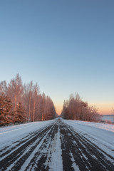 Fototapeta na wymiar Snow-covered road in rural Russia of a frosty morning, around a field and forest