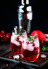 Red cocktail vodka pomegranate juice, with ice and rosemary, bar tools, blue bar counter background, top view