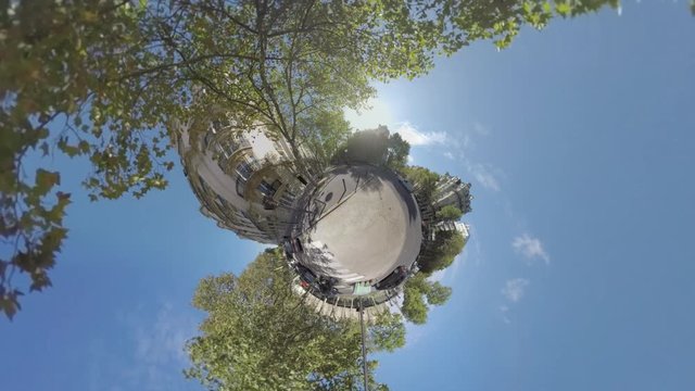 Timelapse spherical shot of the city. Street with people, buildings and green trees. Little planet effect