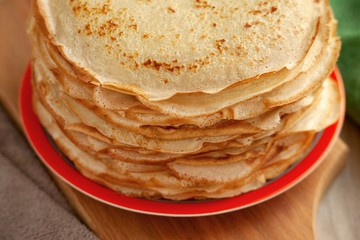 A stack of thin pancakes close-up. Pancake week. Porous thin pancakes on a bright saucer on the...