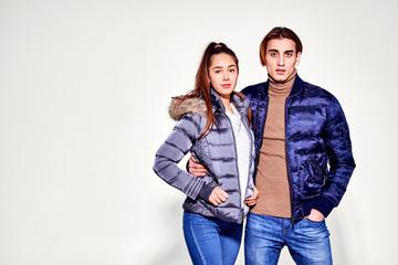 Fashion shot. Couple of young people in winter clothes posing at studio. Autumn and winter clothes.