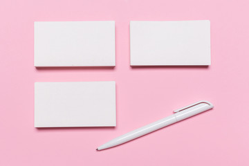 Blank white business cards on pink background.