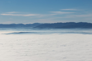 Fog filling a valley in Umbria (Italy), with layers of mountains and hills, various shades of blue
