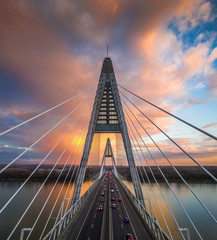 Budapest, Hungary - Aerial view of Megyeri Bridge over River Danube with beautiful golden sky and clouds and heavy traffic at sunset