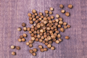 Heap of coriander seeds on wooden background. Top view