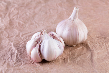 Two garlic bulbs on the crumpled craft paper background. Closeup