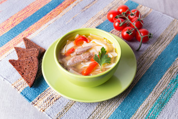 Chicken soup with noodles in a plate with tomato branch and bread