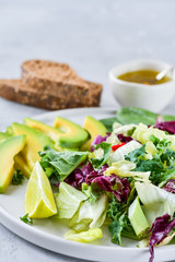 salad  of avocado, egg, green kale and spinach. olive oil in a white cup. on a white plate, grain bread, diet food, organic vegetables.  food flat lay, salad recipe,  light background