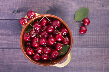 Heap of red cherries in a bowl on wooden background. Fresh delicious berries on  boards.
