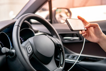 Male driver sitting with steering wheel using smartphone for GPS navigation. Mobile phone mounting with magnet on the car console in modern car. Urban driving lifestyle with mobile app technology