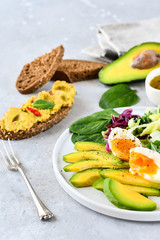 food for a healthy Breakfast or lunch. salad of avocado, kale leaves, egg and spinach, on a white plate, grain bread, diet food, organic vegetables, food flat lay