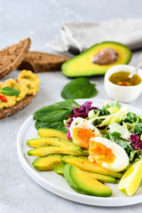 food for a healthy Breakfast or lunch. salad of avocado, kale leaves, egg and spinach, on a white plate, grain bread, diet food, organic vegetables, food flat lay
