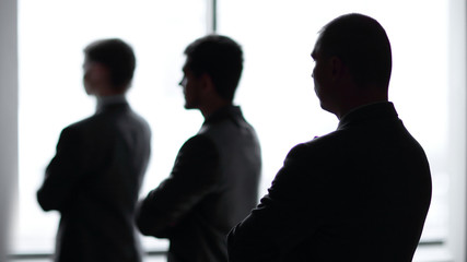 back view three employees as they look out on a large window overlooking the city