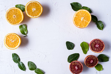 Flat lay the raw fresh citrus fruit - yellow and red orange fruit and lime leaves.