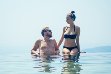 happy couple in the pool looking at mountain landscape in India Goa Kerala wildernest luxury resort . Man and woman together enjoying beautiful mountains on summer travel