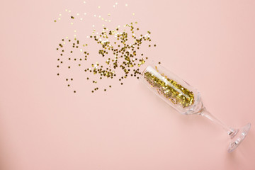 Champagne glasses with golden stars confetti on beige color paper background minimal style