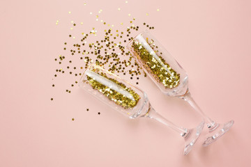 Champagne glasses with golden stars confetti on beige color paper background minimal style