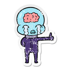 distressed sticker of a cartoon big brain alien crying but giving thumbs up symbol