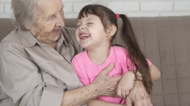 Grandmother tickles a granddaughter with love. Granny is having fun with her little granddaughter.