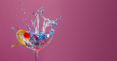 Cocktail in glass with splashes garnished with lemon and cherries.