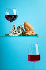Blue cheese with bread,  rosemary and glasses of wine on a blue background.