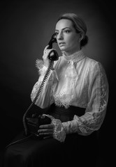 Portrait of a woman in retro clothes with a old black phone.