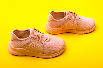 Kid's fashion pink boots on color background. Stylish new shoes on yellow background.