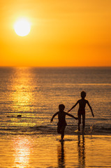 Children play in the sea at sunset.